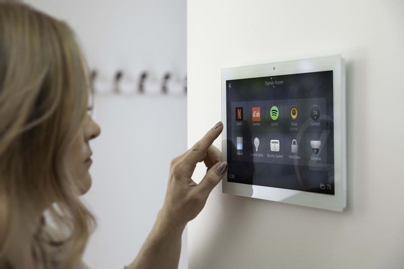 A woman is pointing at a smart device on the wall during a smart home installation.