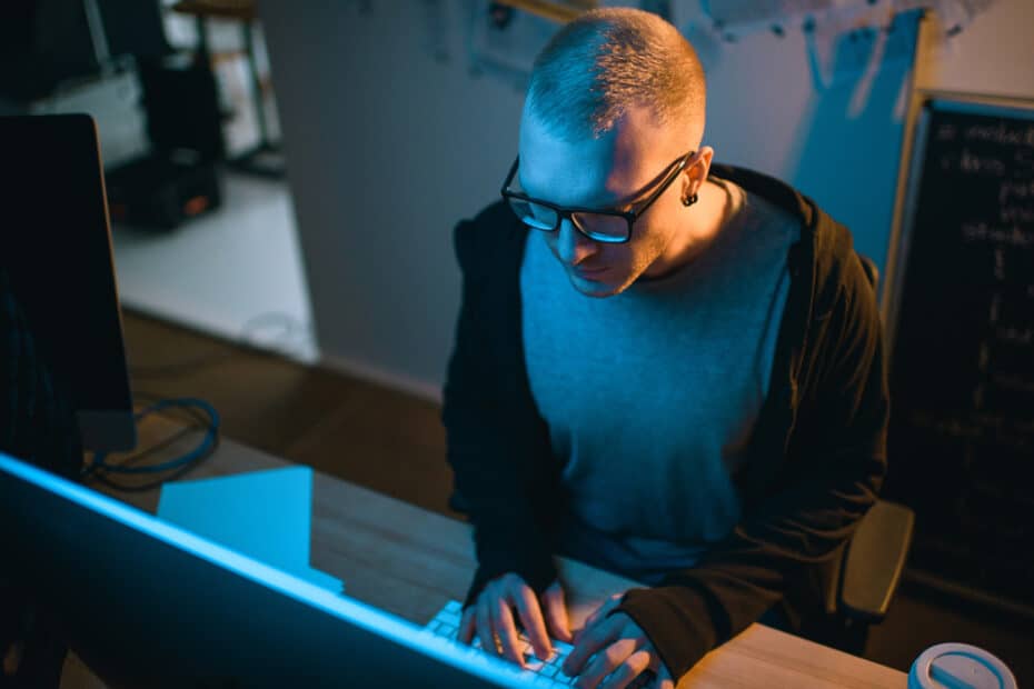 A former NSA hacker diligently working on a computer in a dimly lit room, sharing essential tips to protect yourself online.